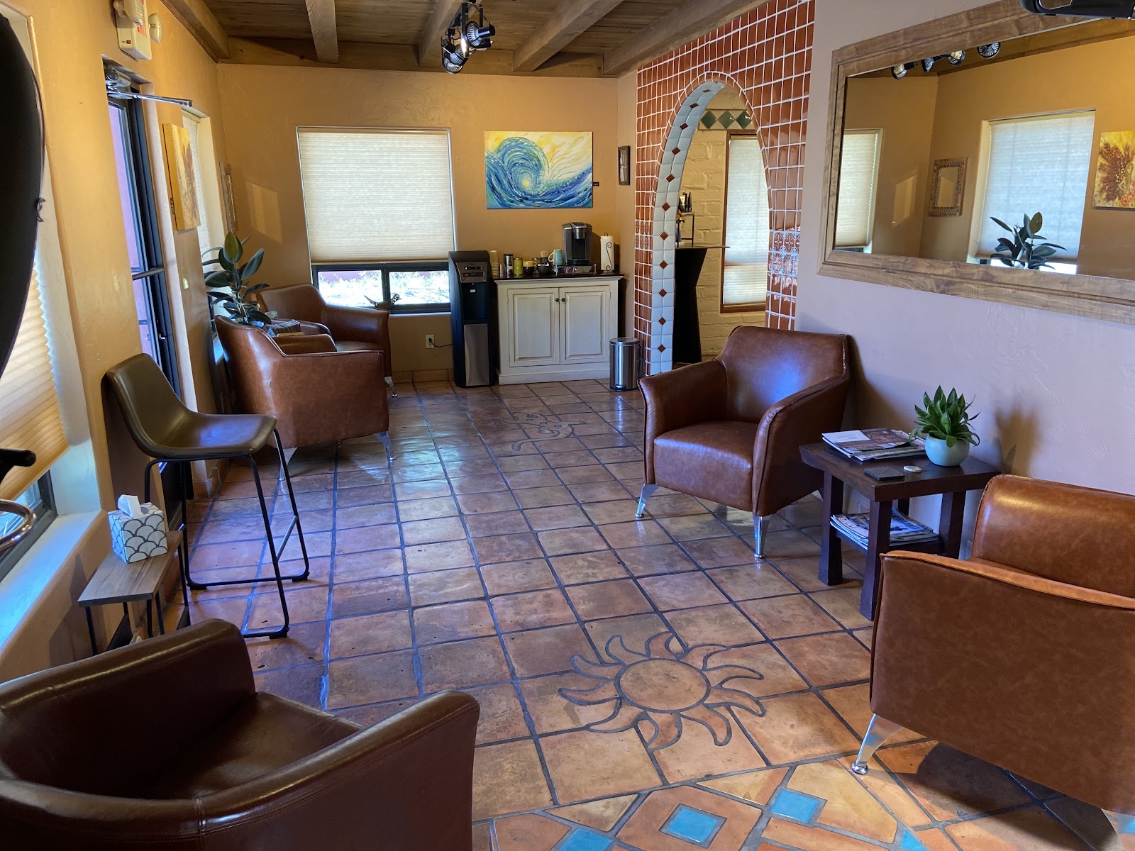 The Gloss Studio lobby, with leather chairs, a tiled archway and a sun set into the saltillo-tile floor